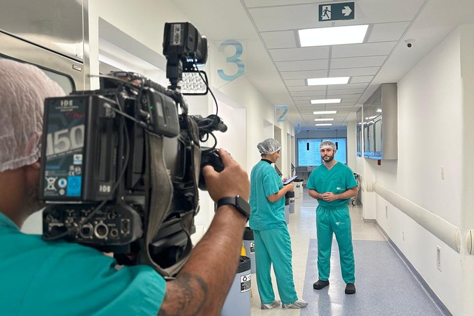 Equipe de TV gravando entrevista com médico em corredor de hospital